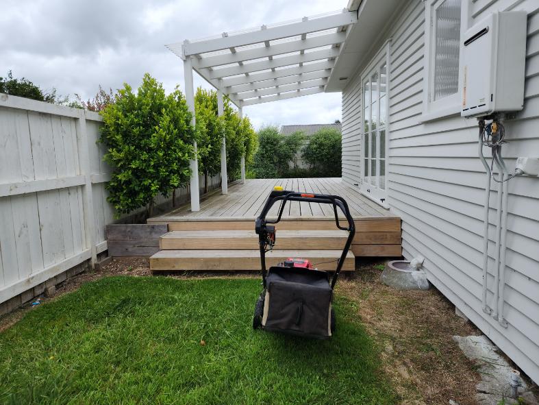 Small back lawn mowed beside a timber deck at a Waihi home